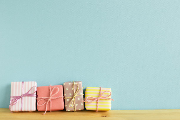 木桌上放着五颜六色的礼品盒。天空的蓝色背景图片下载