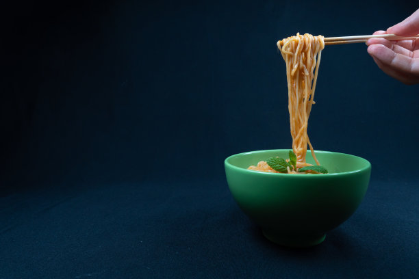 鸡四川面或客家面或炒面在黑色的碗在黑暗的背景。图片下载