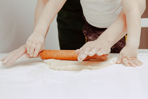 幸福的家庭在厨房。爸爸和儿子准备面团，烤饼干。休闲的生活方式，漂亮的孩子，节日概念，擀面杖，曲奇切割机和面团。图片下载