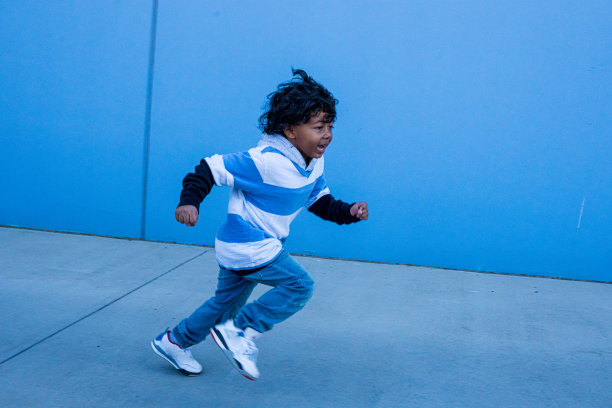 小混血男孩在蓝色的墙上跑图片下载