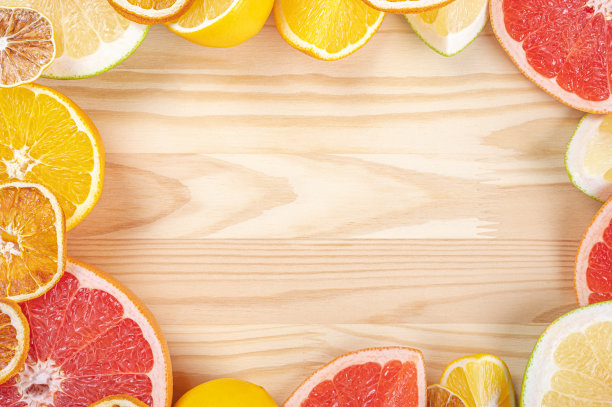 木桌上的柑橘框模板。不同的多汁柑橘类水果切片。带有文本空间的框架图片下载