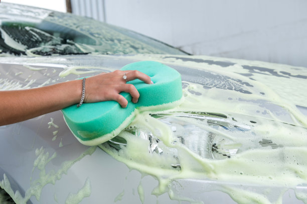 女人的手用海绵和肥皂泡沫清洗她的车图片下载