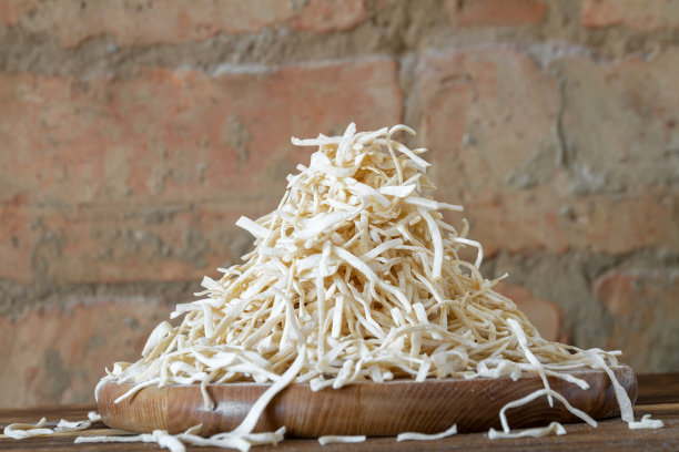 在一堵红砖墙的背景上，一块圆形木板上撒着自制的干面条或意大利面，上面放着滑梯图片下载