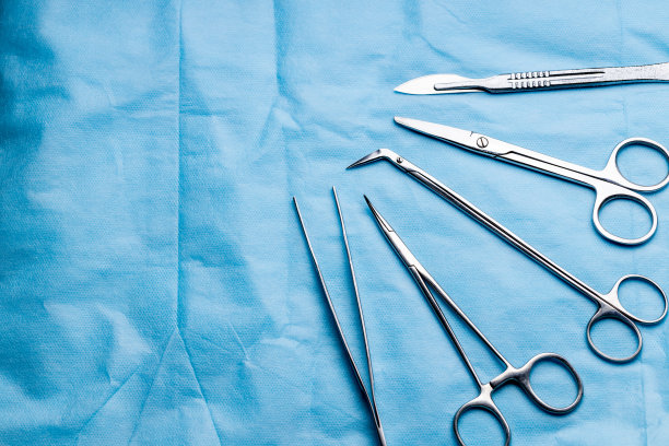 手术台上的手术台。医疗工具，如剪刀，手术刀，镊子，蓝色背景。手术的概念图片下载