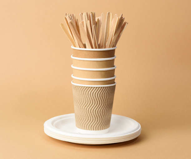 纸杯，白色盘子和木制的刀叉放在棕色的背景上图片下载