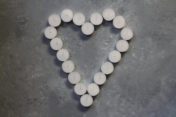 白色的心形蜡烛在石头的背景上，情人节的概念图片下载