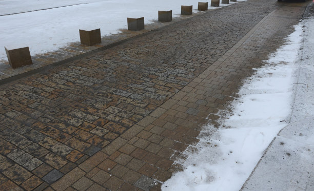 铺砌的立方体花岗岩道路在城市中以立方体石砌为界。它是行人进入步行区之间的入口障碍。路面上撒满了湿盐。的人行道上图片下载