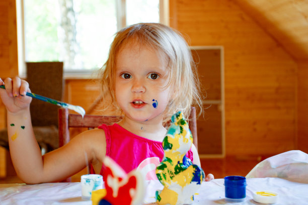 家庭教育:可爱的学步小女孩用丙烯酸颜料涂鸟图片下载