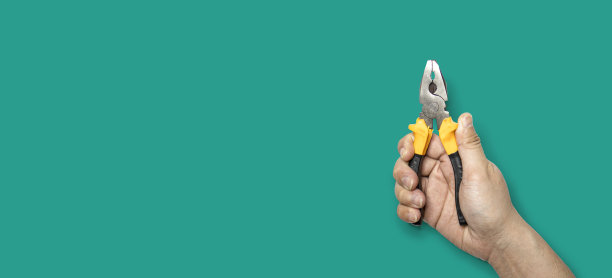 手持黄柄钳子的人。图片下载