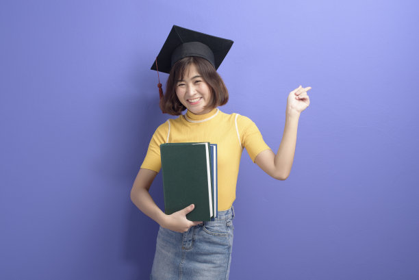 年轻的亚洲学生的肖像戴着毕业帽在工作室的背景。图片下载