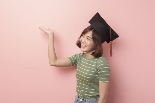 年轻的亚洲学生的肖像戴着毕业帽在工作室的背景。图片下载
