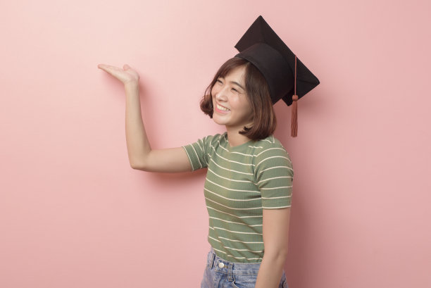 年轻的亚洲学生的肖像戴着毕业帽在工作室的背景。图片下载