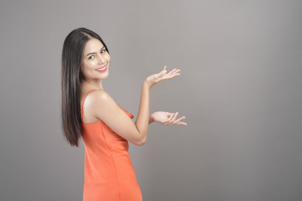 时尚肖像美丽的女人穿着橙色连衣裙孤立在灰色背景的工作室图片下载
