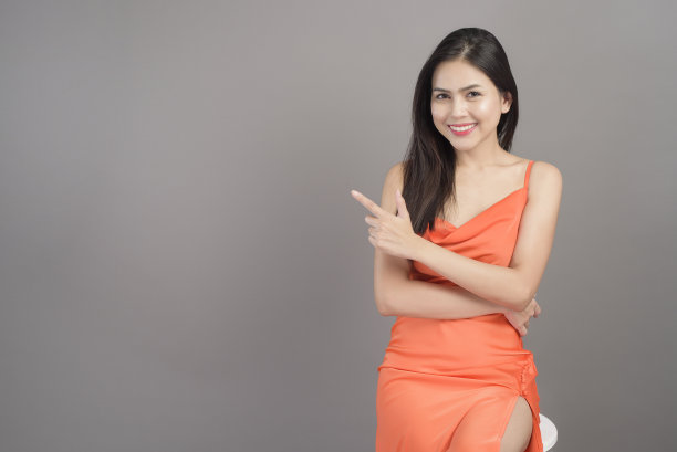 时尚肖像美丽的女人穿着橙色连衣裙孤立在灰色背景的工作室图片下载