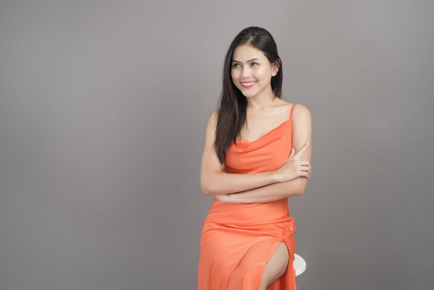 时尚肖像美丽的女人穿着橙色连衣裙孤立在灰色背景的工作室图片下载