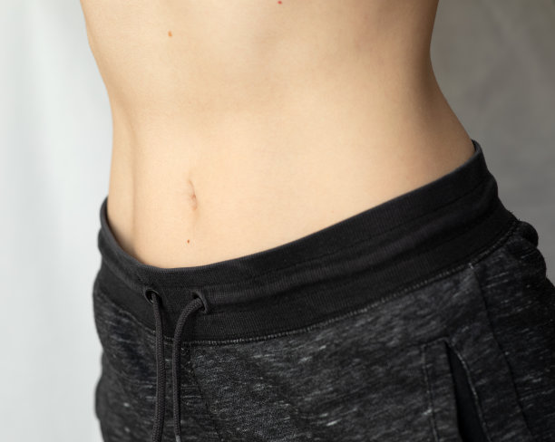 女性腹部平坦。女人露出她平坦的腹部。身体部位:运动年轻女性的腹部。腹部可见痣图片下载