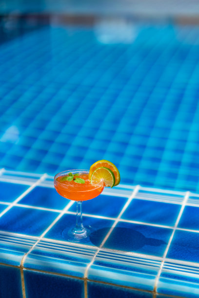 在泳池边喝一杯热带橙色鸡尾酒图片下载