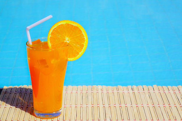 在游泳池里喝新鲜橙汁。图片下载