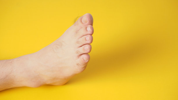 光脚的男性被隔离在黄色背景上。图片下载