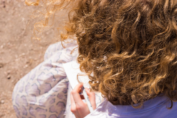 卷曲的金发女性画在纸上。女孩向后看。女性艺术家特写图片下载