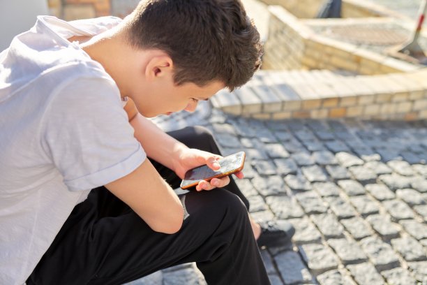 16、17岁的少年，坐在夏城的街头，用着智能手机图片下载