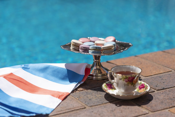 游泳池边的银托盘上放着茶和法式马卡龙图片下载