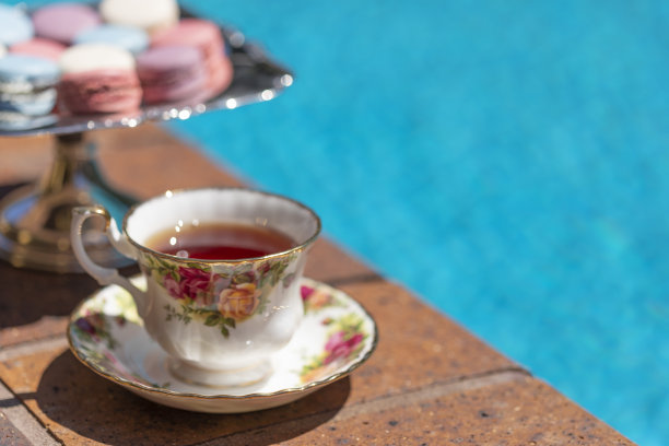 游泳池边的银托盘上放着茶和法式马卡龙图片下载