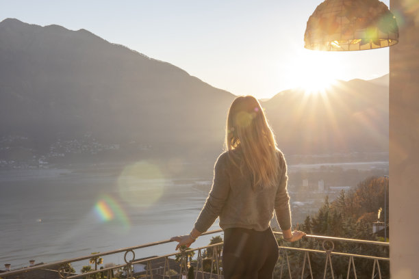 日出时，年轻女子在阳台上休息图片下载