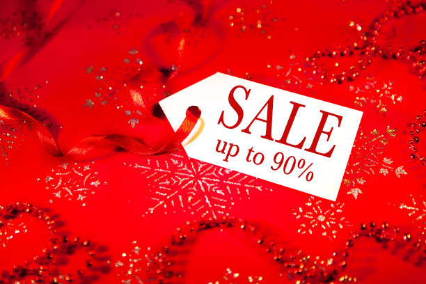 在圣诞节和新年假期期间，在装饰过的圣诞背景上贴上印有“打折”字样的标签。图片下载