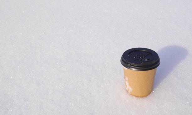 纸杯上放着芳香的热拿铁咖啡，上面放着蓬松的结霜的雪。具有天然芳香成分。图片下载