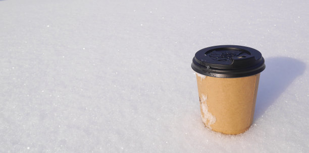 纸杯上放着芳香的热拿铁咖啡，上面放着蓬松的结霜的雪。具有天然芳香成分。图片下载