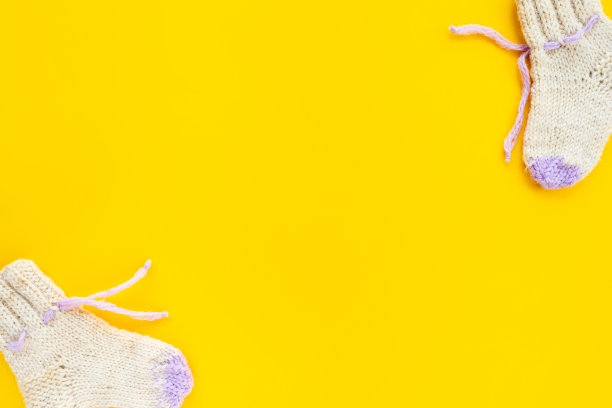 儿童针织羊毛袜子底色为黄色，平整平整，俯视图，复制空间。婴儿的概念。极简主义的婴儿背景新生女孩图片下载