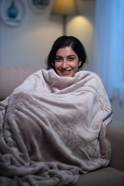 年轻女人坐在家里的沙发上图片下载