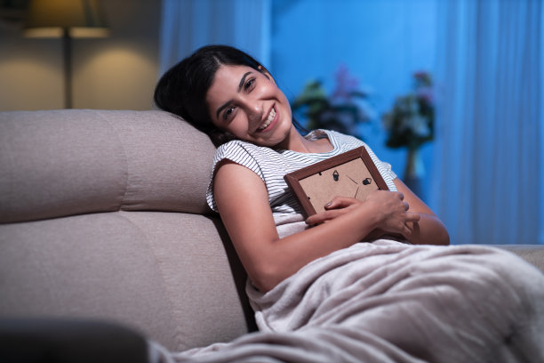 年轻女子在家沙发上坐着，库存照片图片下载