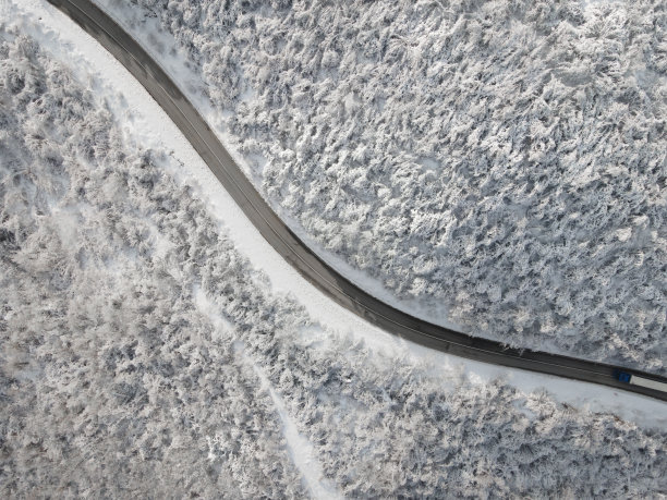 弯弯曲曲的风路在冰雪覆盖的森林，从上往下鸟瞰图片下载