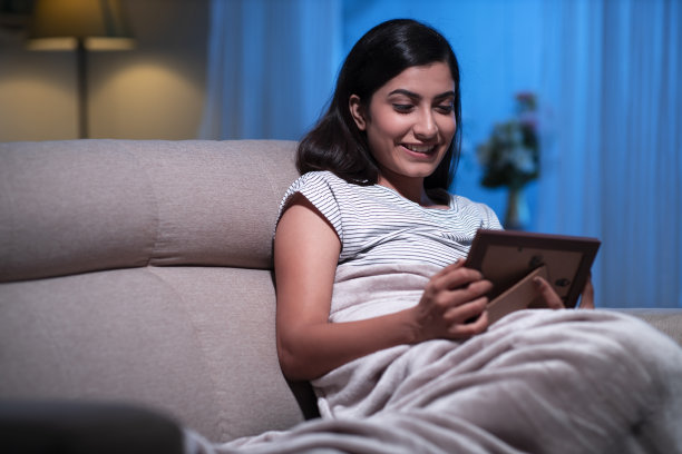 年轻女子在家沙发上坐着，库存照片图片下载