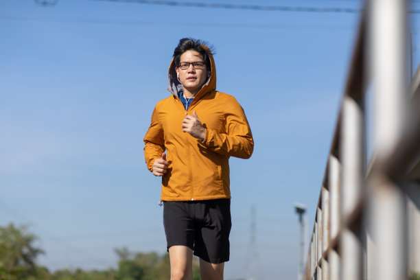 年轻的亚洲人在户外的铁路轨道上跑步。图片下载