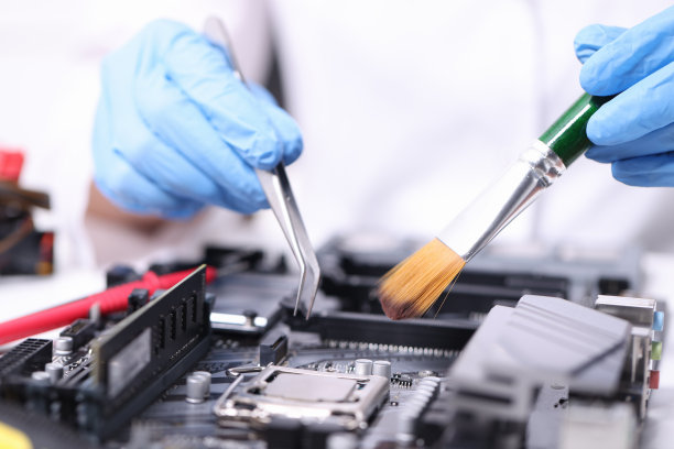 戴手套的杂工用刷子和镊子修理主板图片下载