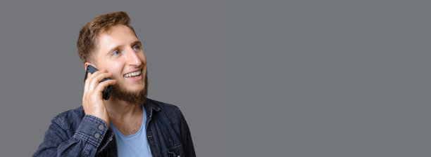 姜男孩是在电话和微笑附近灰色工作室自由空间图片下载