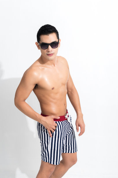 男人在条纹沙滩短裤日光浴。图片下载