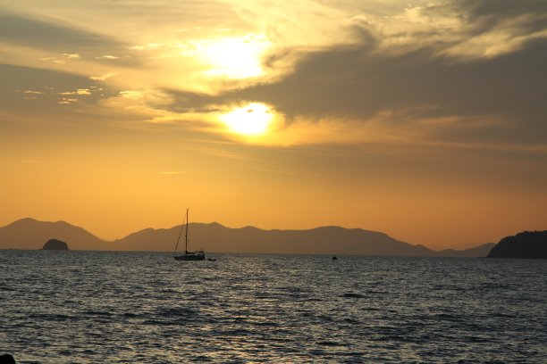 日落海景景观。橙色美丽的夕阳在海上。放松的夜晚。海边的黄昏。放松的假期。海浪，岛屿和天空的云。美丽的晚上。图片下载