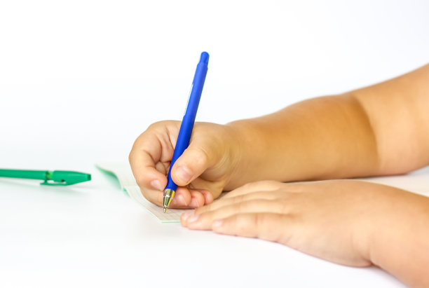 孩子把手放在打开的笔记本上，准备在上面写字。图片下载