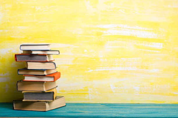 书籍组成与古老的旧精装日记，扇页在木制甲板桌子和黄色背景。书堆积。回到学校。副本的空间。教育背景。图片下载
