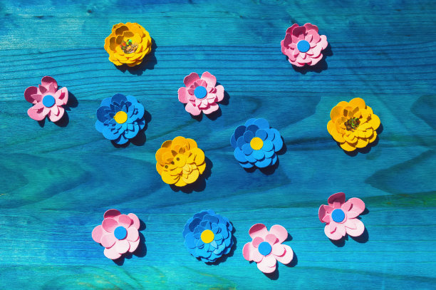 蓝色木质背景上彩色纸花的抽象空地图片下载