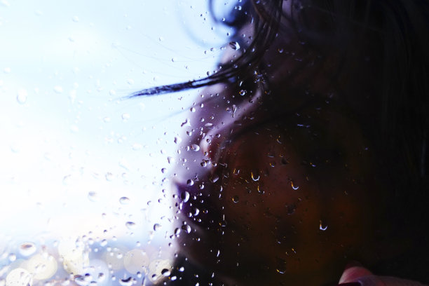 一个悲伤的女人在雨天站在窗前图片下载