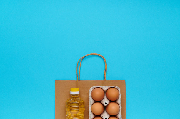 顶视图,flatlay。一套产品与纸袋在蓝色背景。从商店买的食物。葵花籽油，鸡蛋。交付和捐赠概念图片下载