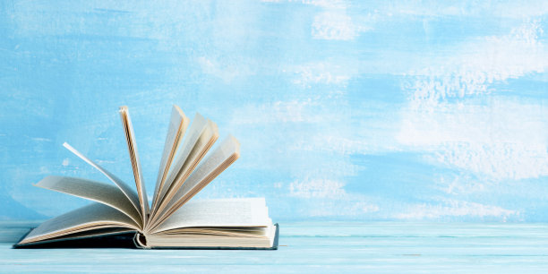 用旧的精装书，日记，扇页木制甲板桌子和蓝色背景组成。书堆积。回到学校。副本的空间。教育背景。图片下载