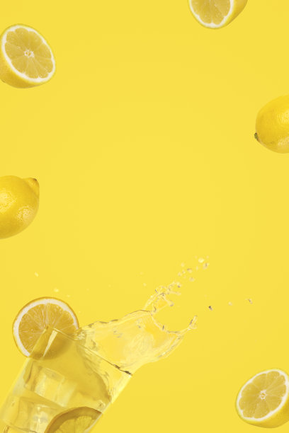 垂直组成的飞行柠檬和一杯新鲜柠檬与冰块落入它，溅起水花。在黄色背景上复制空间。夏天的时间图片下载
