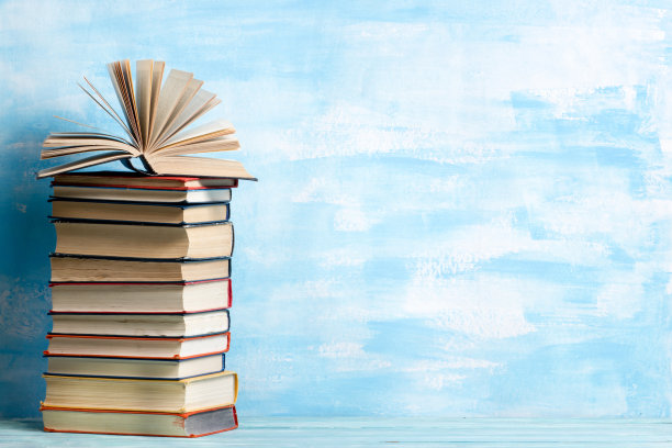 用旧的精装书，日记，扇页木制甲板桌子和蓝色背景组成。书堆积。回到学校。副本的空间。教育背景。图片下载
