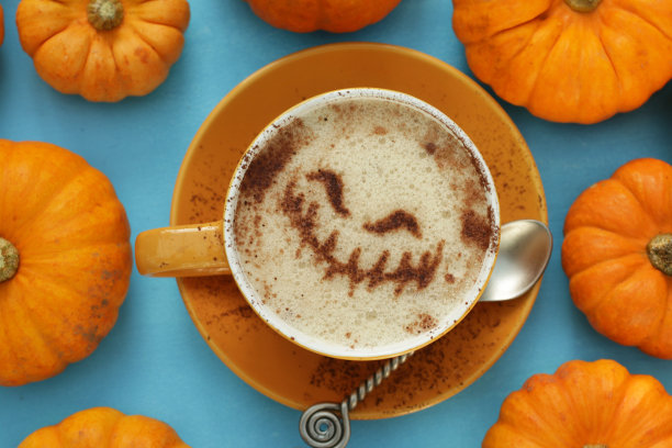 全框，特写图像的橙色杯和碟包含拿铁牛奶泡沫的艺术设计的杰克灯笼包围着橙色的葫芦，蓝绿色的背景，高的视野图片下载